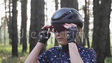 年轻迷人的女孩戴着黑色头盔和蓝色球衣骑自行车前戴上眼镜的肖像。 <strong>单车</strong>概念